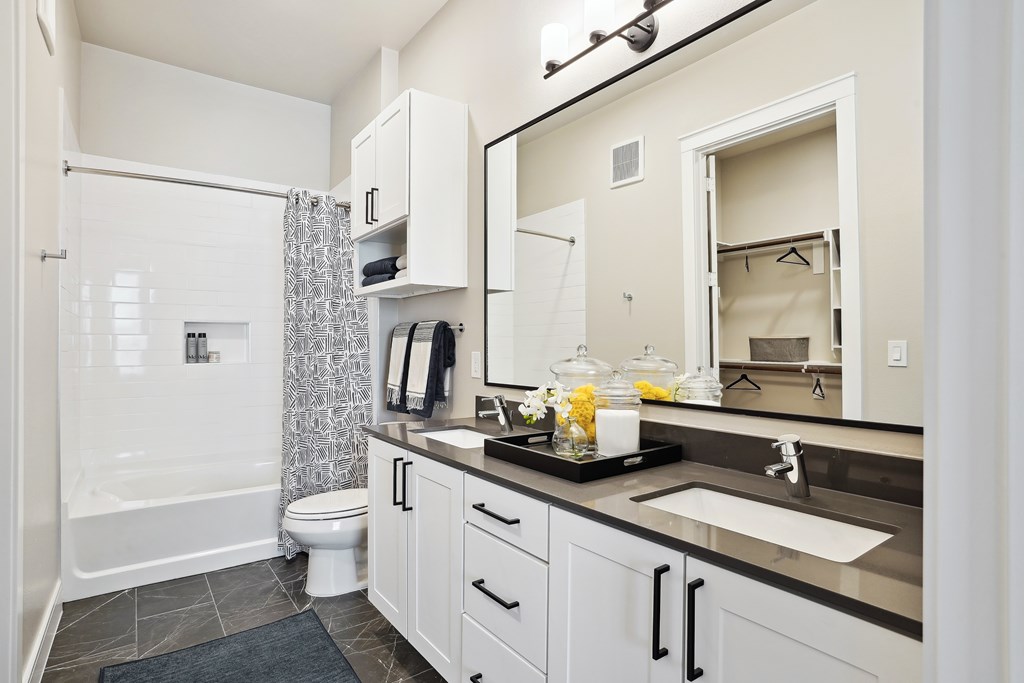 a bathroom with white cabinets and a large dual sink vanity