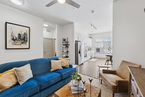 A living room with a blue couch and a painting on the wall.