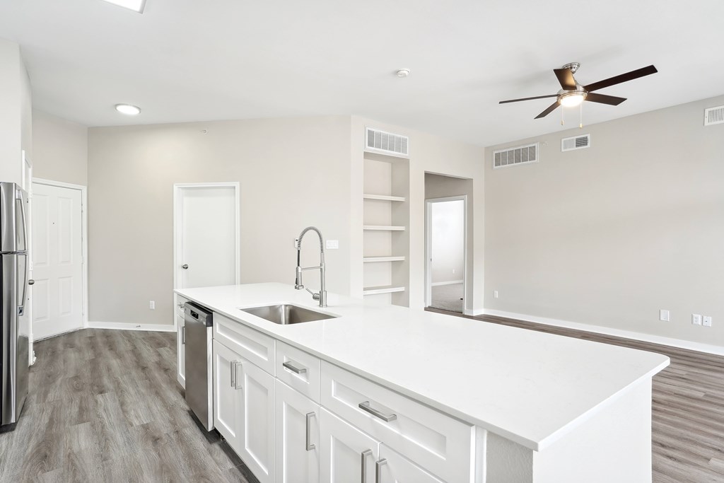 Kitchen with hardwood-style flooring, stainless steel appliances, white quartz countertops, new lighting fixtures, and white cabinetry