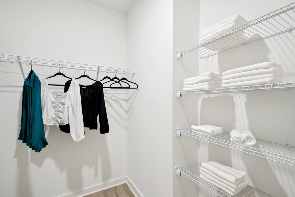 a walk in closet with shelves and racks with towels and clothes