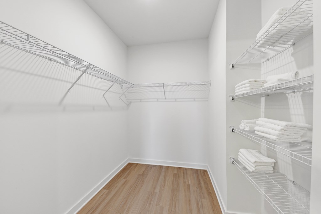 a spacious closet with white walls and wood flooring and a mirrored mirrored closet door
