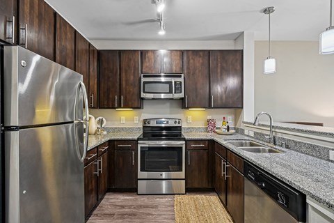 A modern kitchen with dark wood cabinets and stainless steel appliances.
