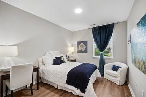 A bedroom with a large bed and a chair.