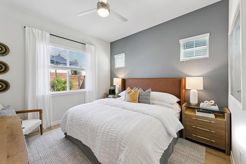 A bedroom with a large bed and a window with curtains.
