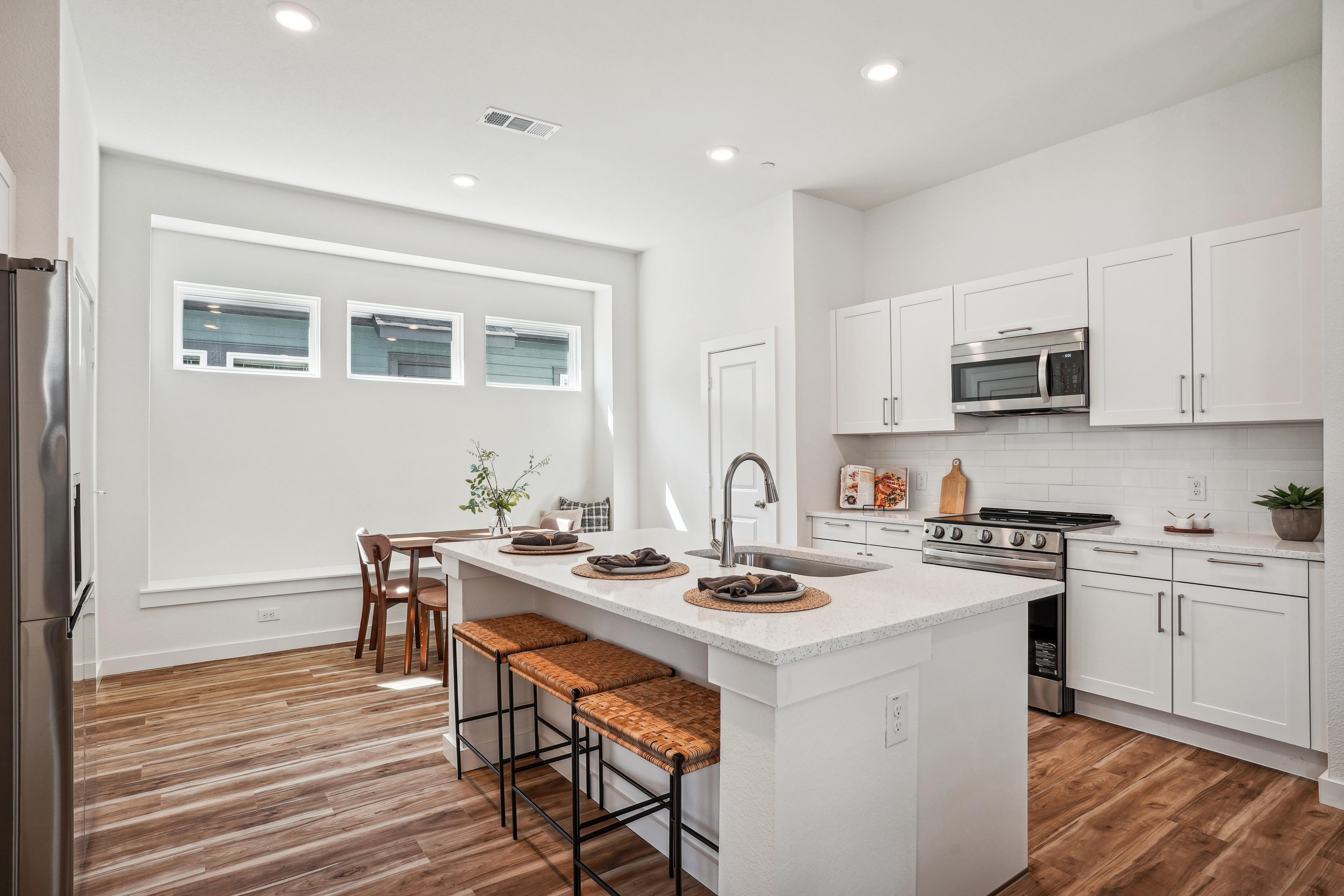 A kitchen with white cabinets and a white island.