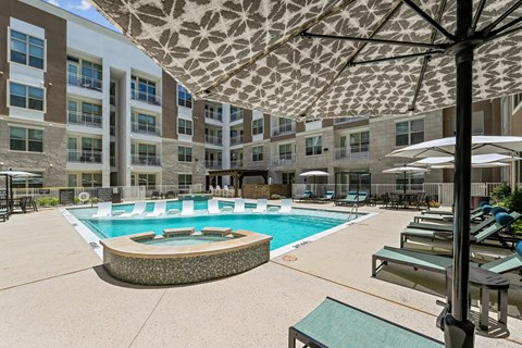 A large umbrella shades a pool area with lounge chairs.