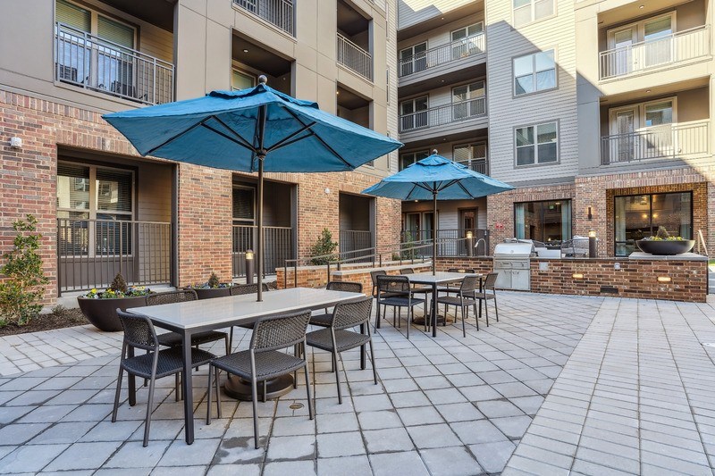 an outdoor patio with tables and umbrellas in an apartment building
