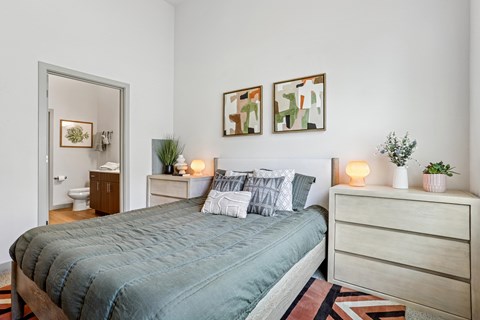 A bedroom with a bed, nightstand, and two framed pictures on the wall.