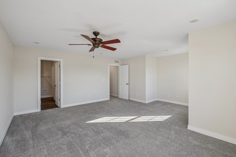 A room with a ceiling fan and carpeted floor.
