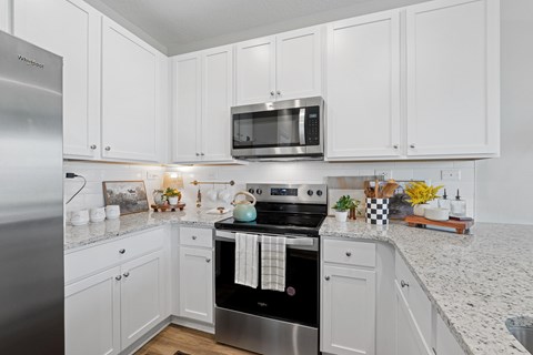 A kitchen with white cabinets and a stainless steel refrigerator.