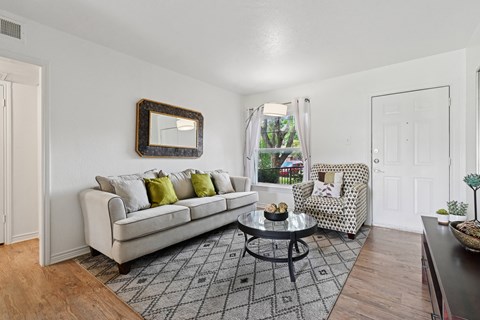 A living room with a white couch, a coffee table, and a chair with a patterned cushion.
