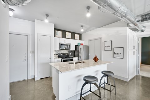 a kitchen with a bar and stools in front of a counter top