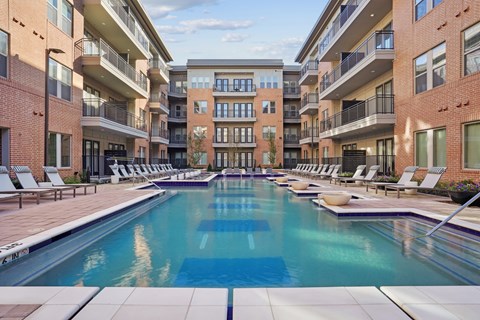 A large swimming pool in the middle of a courtyard surrounded by apartment buildings.