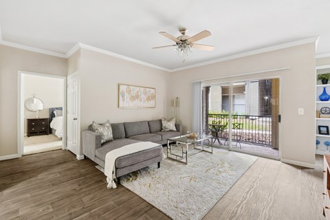 A living room with a grey couch and a ceiling fan.