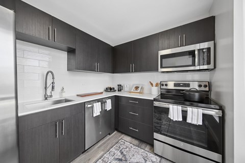 A modern kitchen with dark wood cabinets and stainless steel appliances.