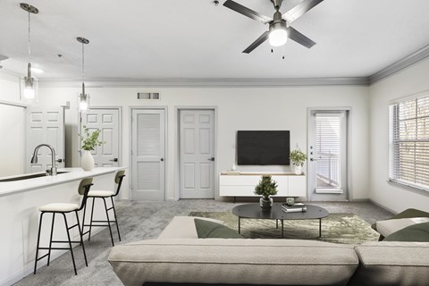 A living room with a grey couch, a white counter, and a ceiling fan.