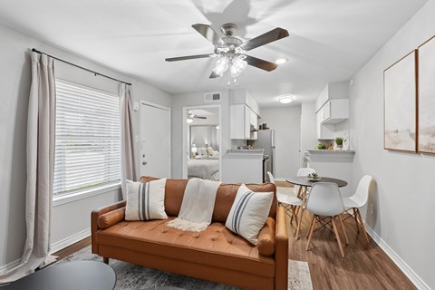 A living room with a brown couch and a ceiling fan.