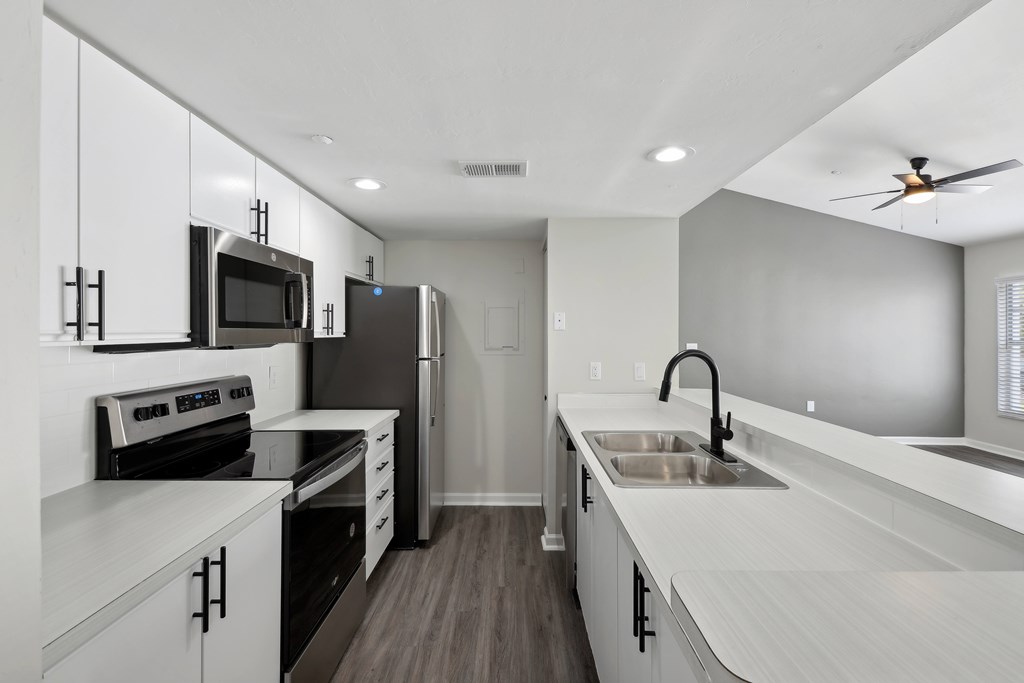 a kitchen with white cabinets and black appliances and a sink