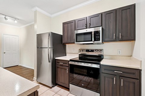 A kitchen with a stove, oven, refrigerator, and microwave.