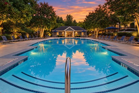 A swimming pool surrounded by lounge chairs and trees.