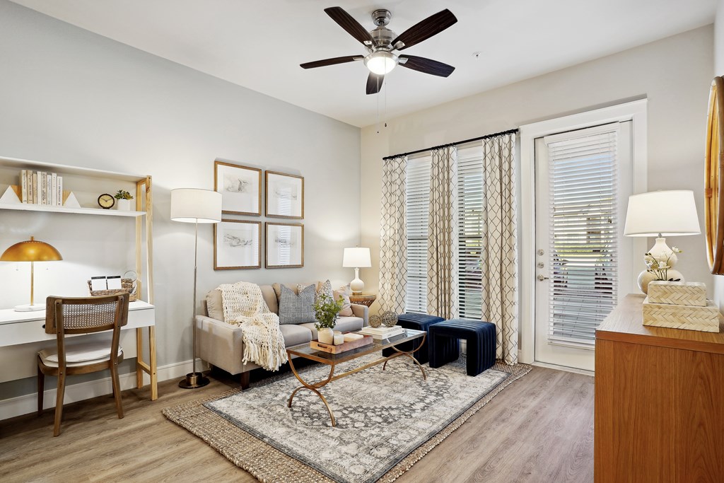 a living room with a desk area and a ceiling fan