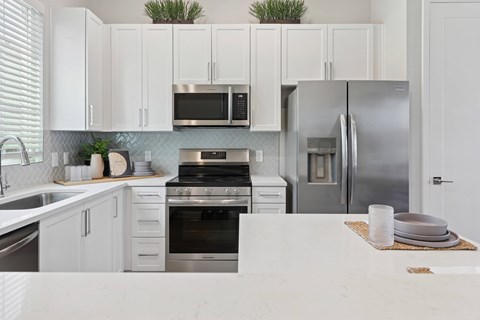 A kitchen with white cabinets and appliances.