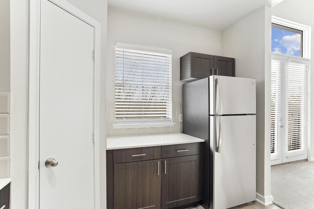 Modern kitchen with stainless steel appliances, quartz countertops, designer tile backsplash, custom cabinetry, and wood-style flooring