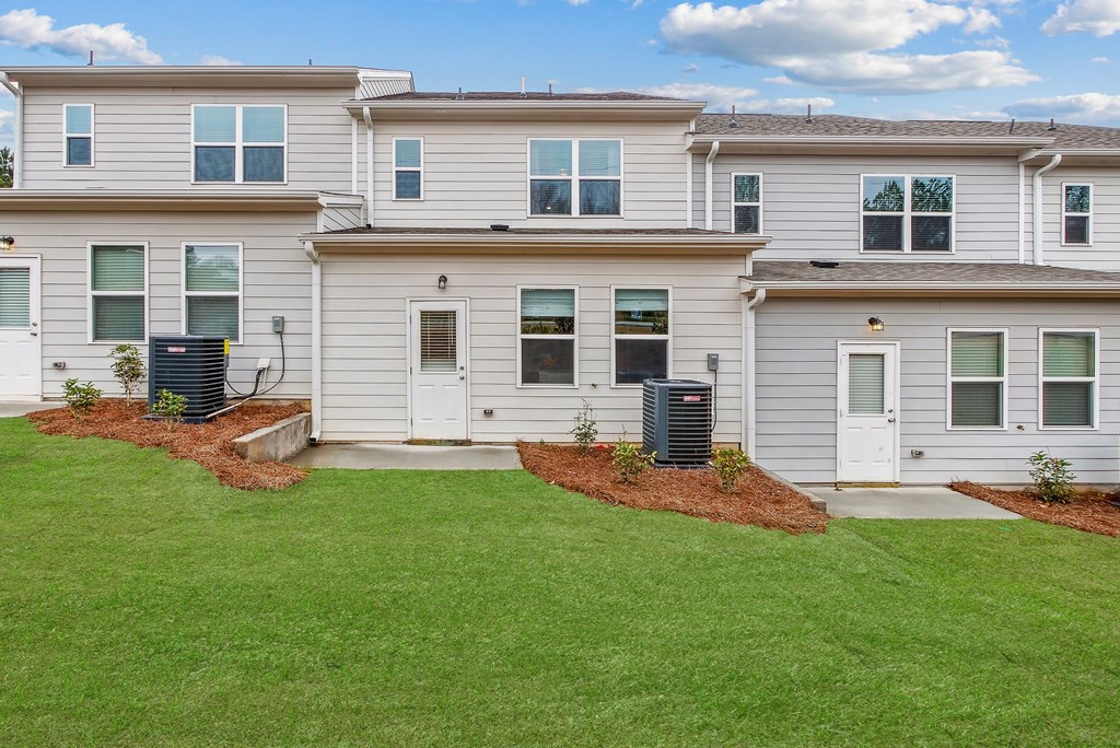 the front of a white house with a lawn and a backdoor