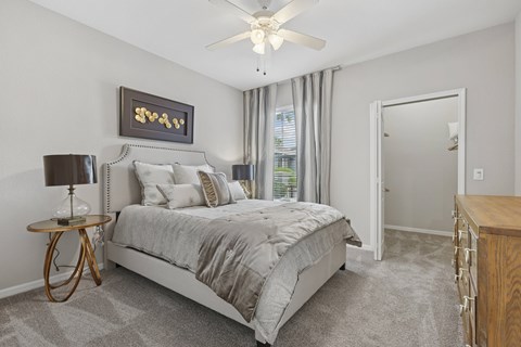 A bedroom with a large bed and a ceiling fan.