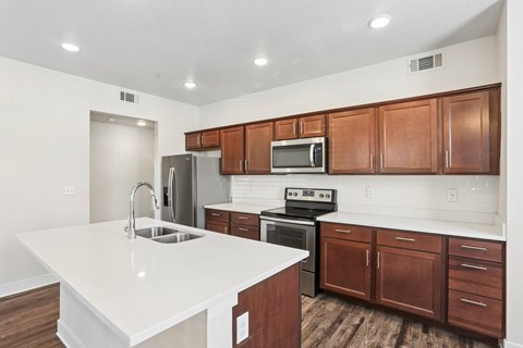 A kitchen with white countertops and wooden cabinets.
