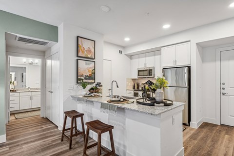 A kitchen with white cabinets and a marble countertop.