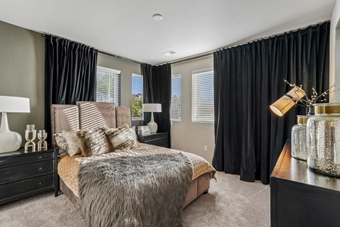 A bedroom with a large bed and a window with black curtains.
