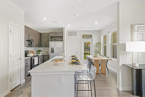 a white kitchen with a large island and a dining table