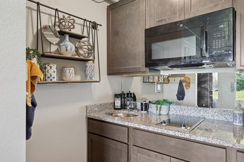 A kitchen with a microwave oven mounted above a countertop with a sink.