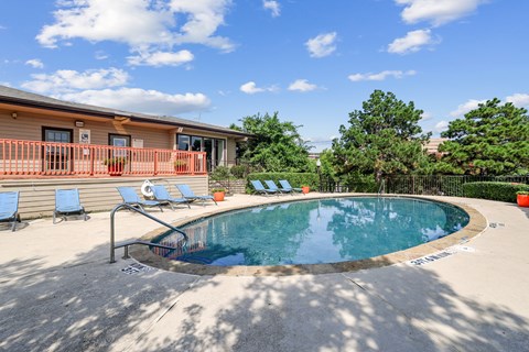 A small pool with a metal railing and a few chairs.