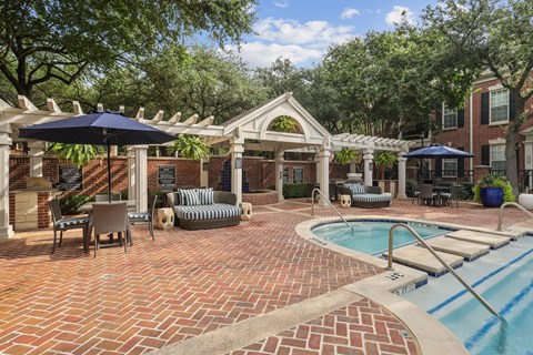 A pool area with a brick patio and a small pool.