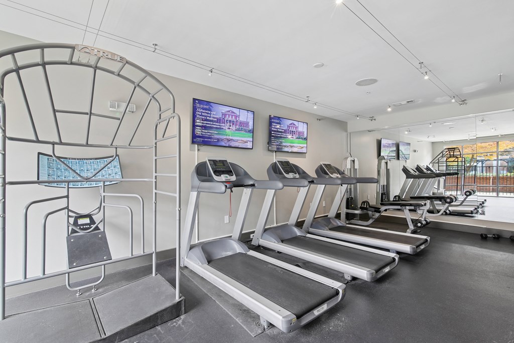A gym with treadmills and a television screen.