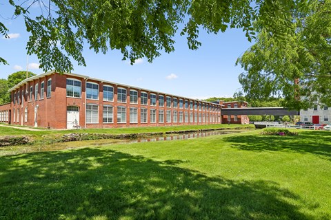 A red brick building with a green lawn in front.