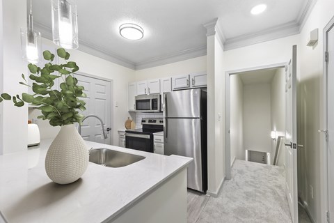 A kitchen with a white counter top and a vase with a plant in it.