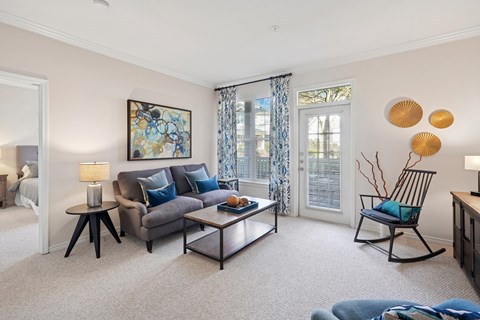A living room with a grey couch, a coffee table, and a painting on the wall.