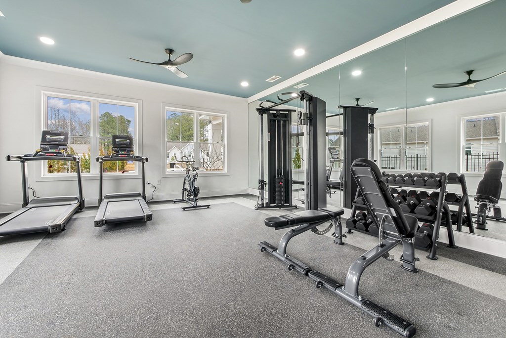 a home gym with weights and cardio equipment and windows