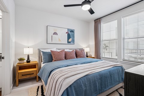 A bedroom with a bed, a nightstand, and a ceiling fan.