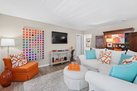 A living room with a white couch and orange accents.