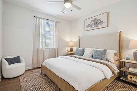 A bedroom with a large bed and a chair.