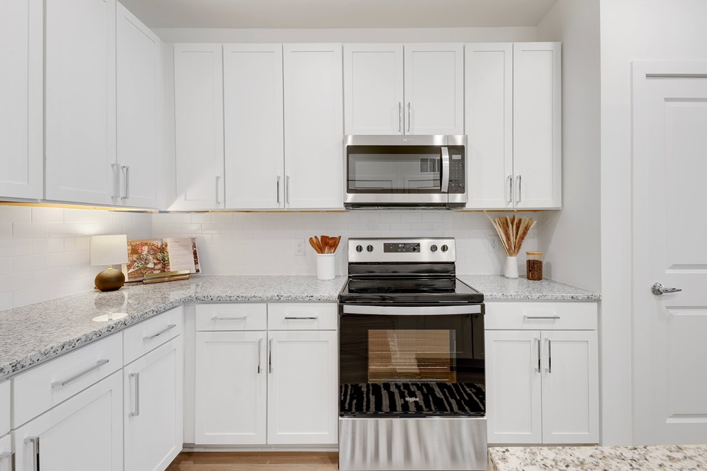 a kitchen with white cabinets and a stove and microwave