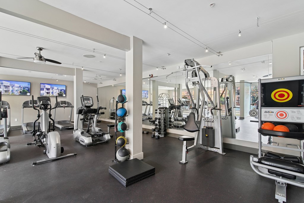 A gym with a variety of exercise equipment including treadmills, stationary bikes, and weight machines.