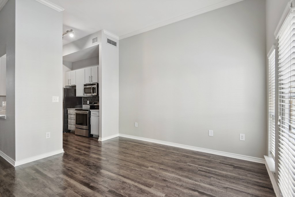 the living room and kitchen of an apartment with wood floors and white walls