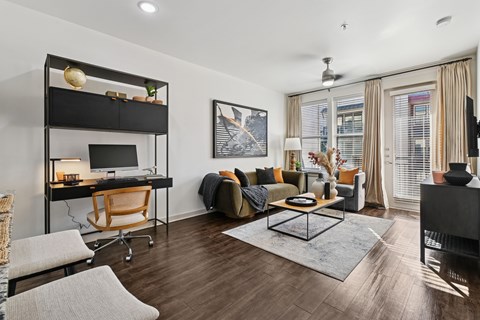 A modern living room with a black sofa and a wooden desk.
