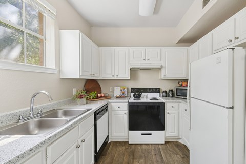 A kitchen with white cabinets and appliances.
