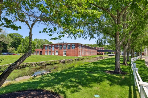 A red brick building with a white fence in front of it.